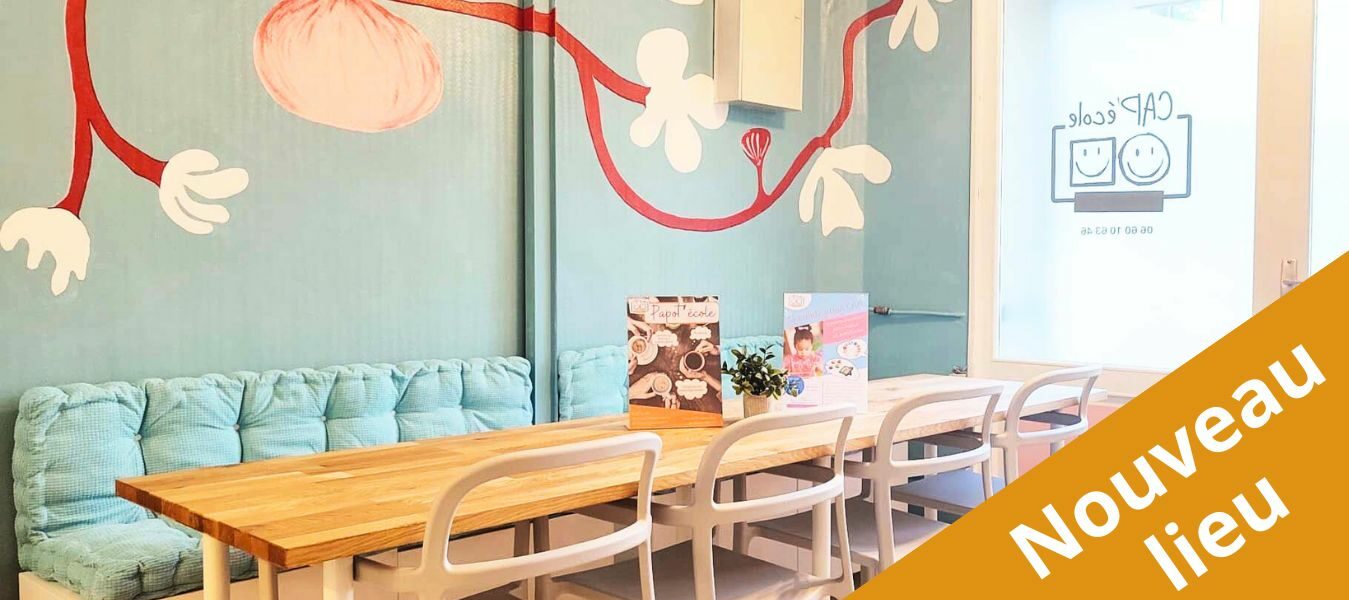 Photo de notre nouveau bureau : une grande table avec des chaises, un mur bleu avec des fleurs peintes dessus.